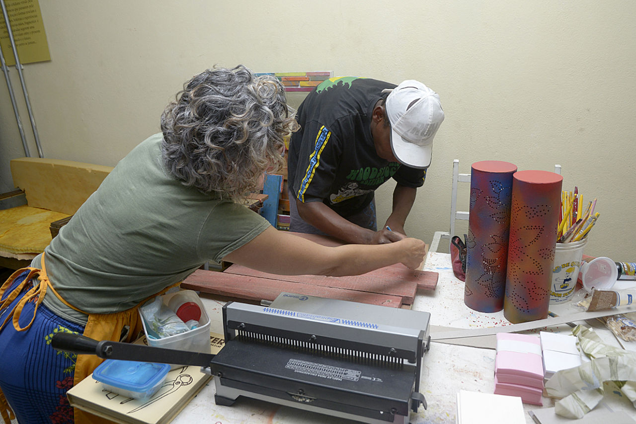 Oficineira dá instruções a aluno do Centro Pop durante oficina de artesanato