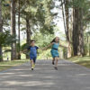 Duas crianças correm de mãos dadas