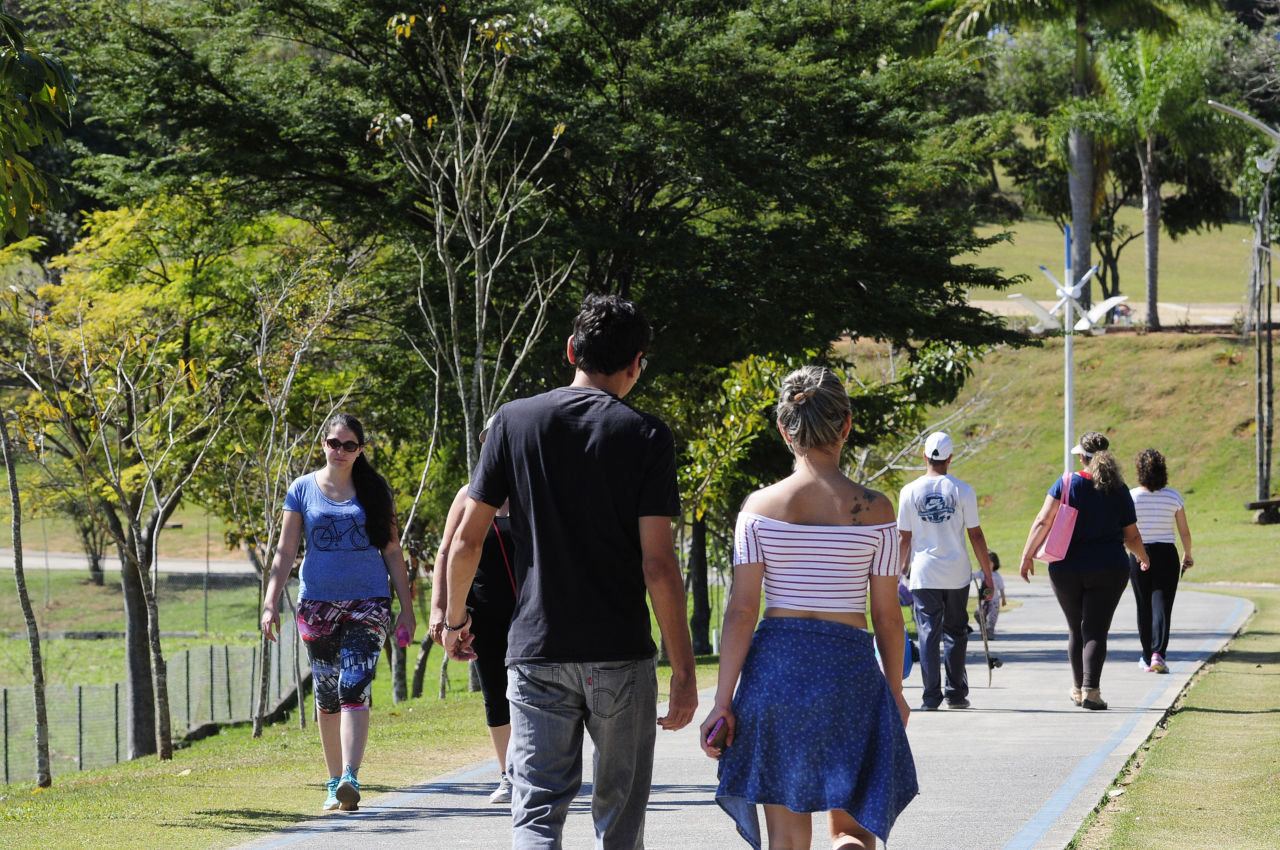 Pessoas caminhando na pista de pedestres do Parque da Cidade, com paisagem e árvores