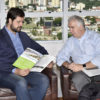 Prefeito Luiz Fernando lê revista ao lado de empresário com a vista de Jundiaí ao fundo