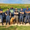 Foto posadas de guardas com cão de trabalho em frente à viatura