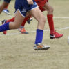 Foto de pernas de jogadores com a bola de futebol no campo