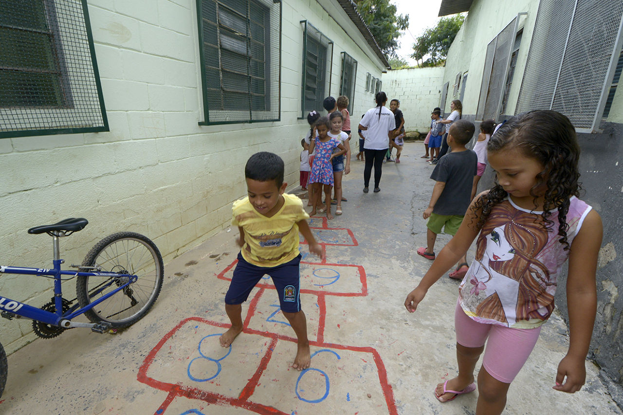 Crianças brincando de amarelinha em corredor de uma casa