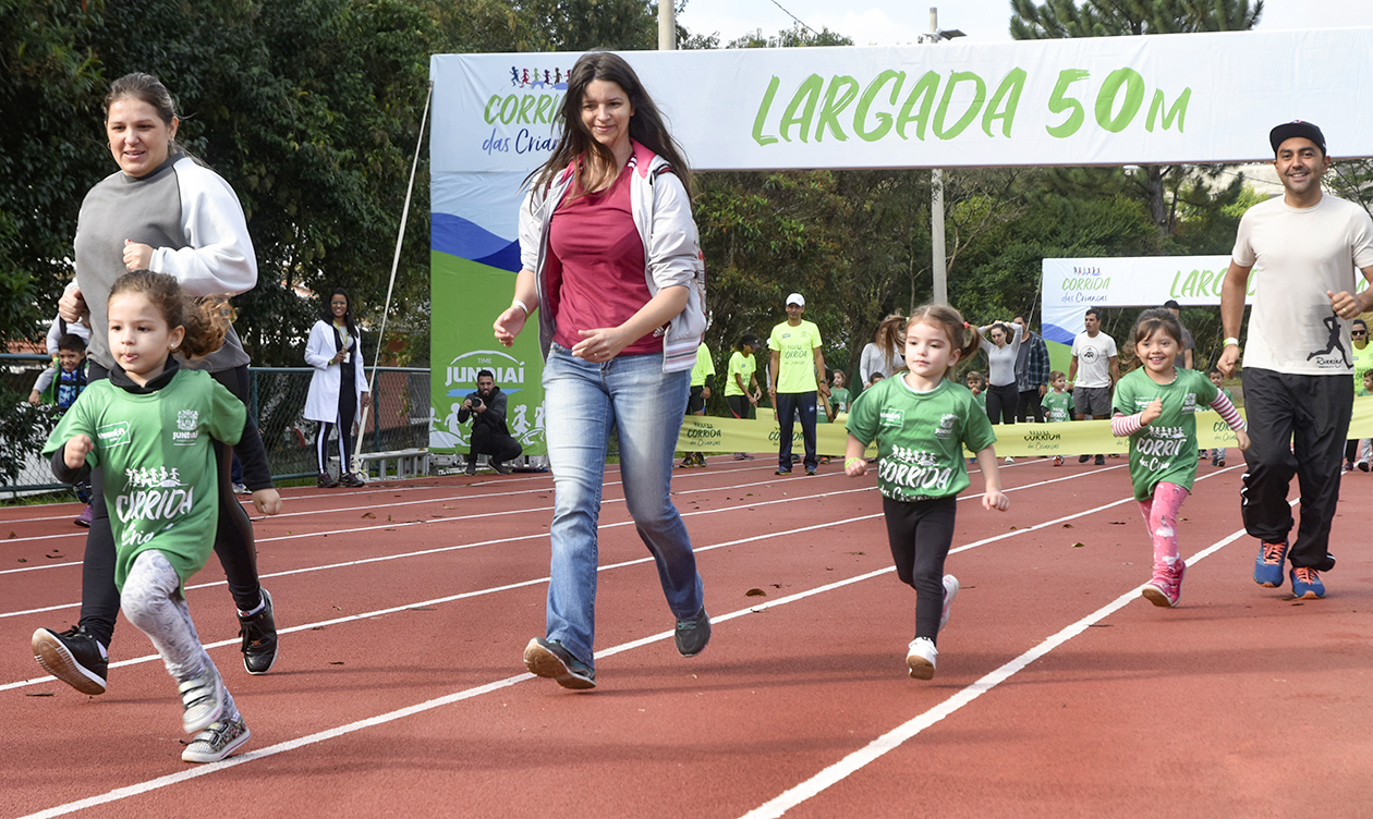 Mulher corre ao lado de criança em pista de atletismo