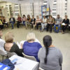 Sala de reunião, com participantes em semicirculo, dentro de sala de aula