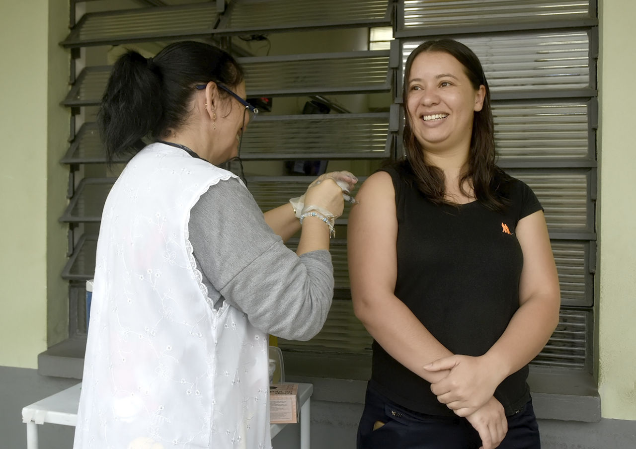 Técnico faz aplicação de vacina contra gripe no braço direito de mulher