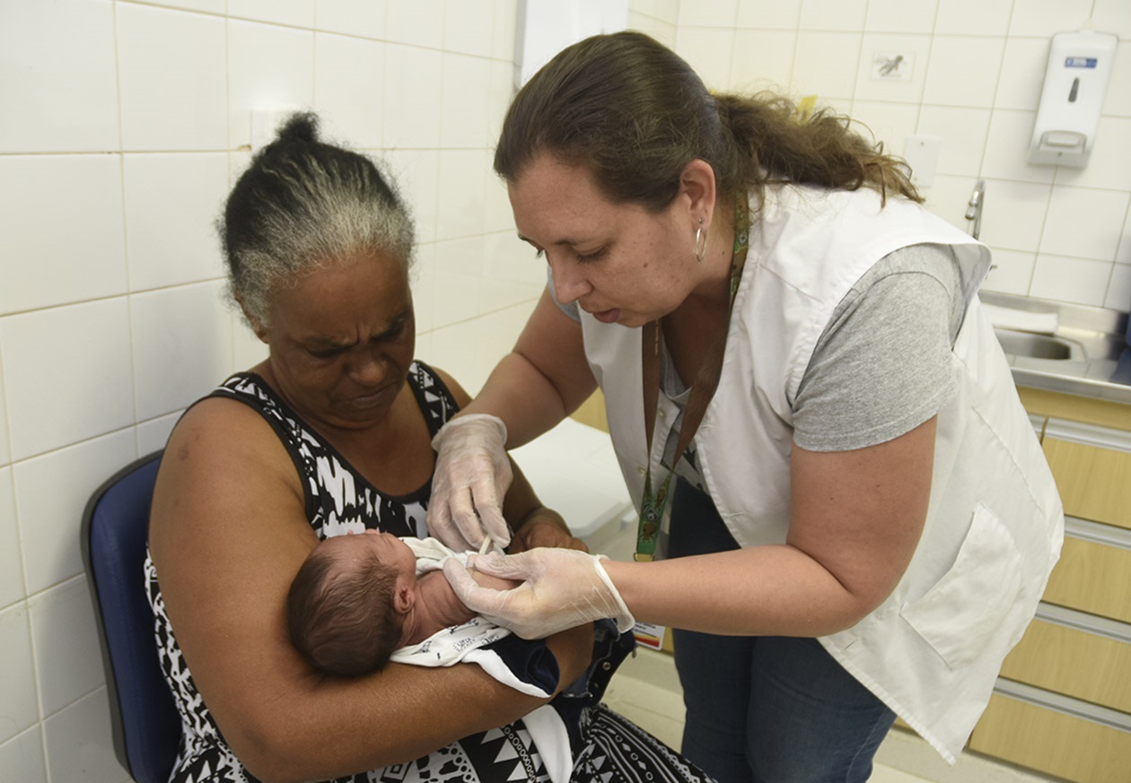 Enfermeira de jaleco aplica vacina em bebê
