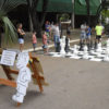 Xadrez em tamanho humano montado em rua do Parque da Uva, com crianças e adultos movendo as peças