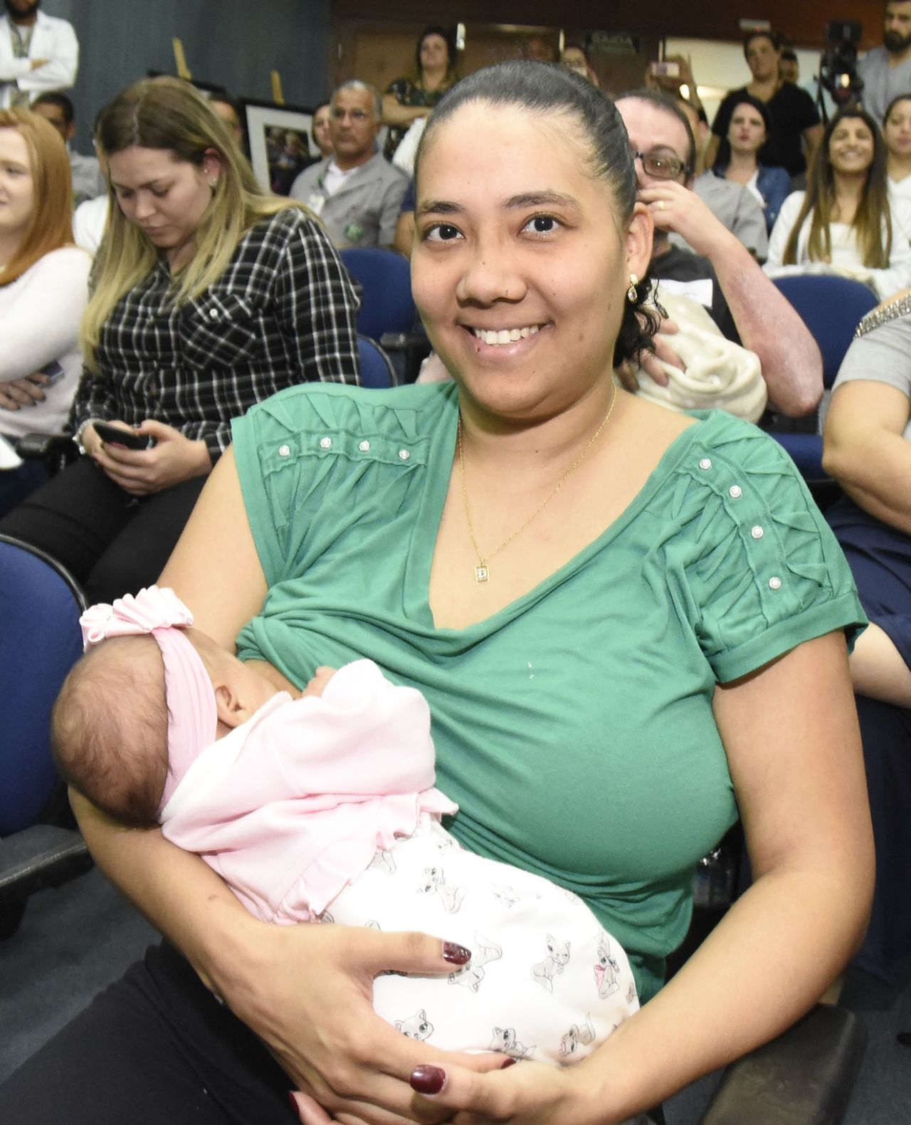 Mulher segura bebê no colo, em foto posada
