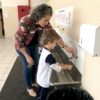 Mulher orienta criança a lavar a mão
