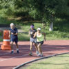 Três pessoas correm na pista de atletismo