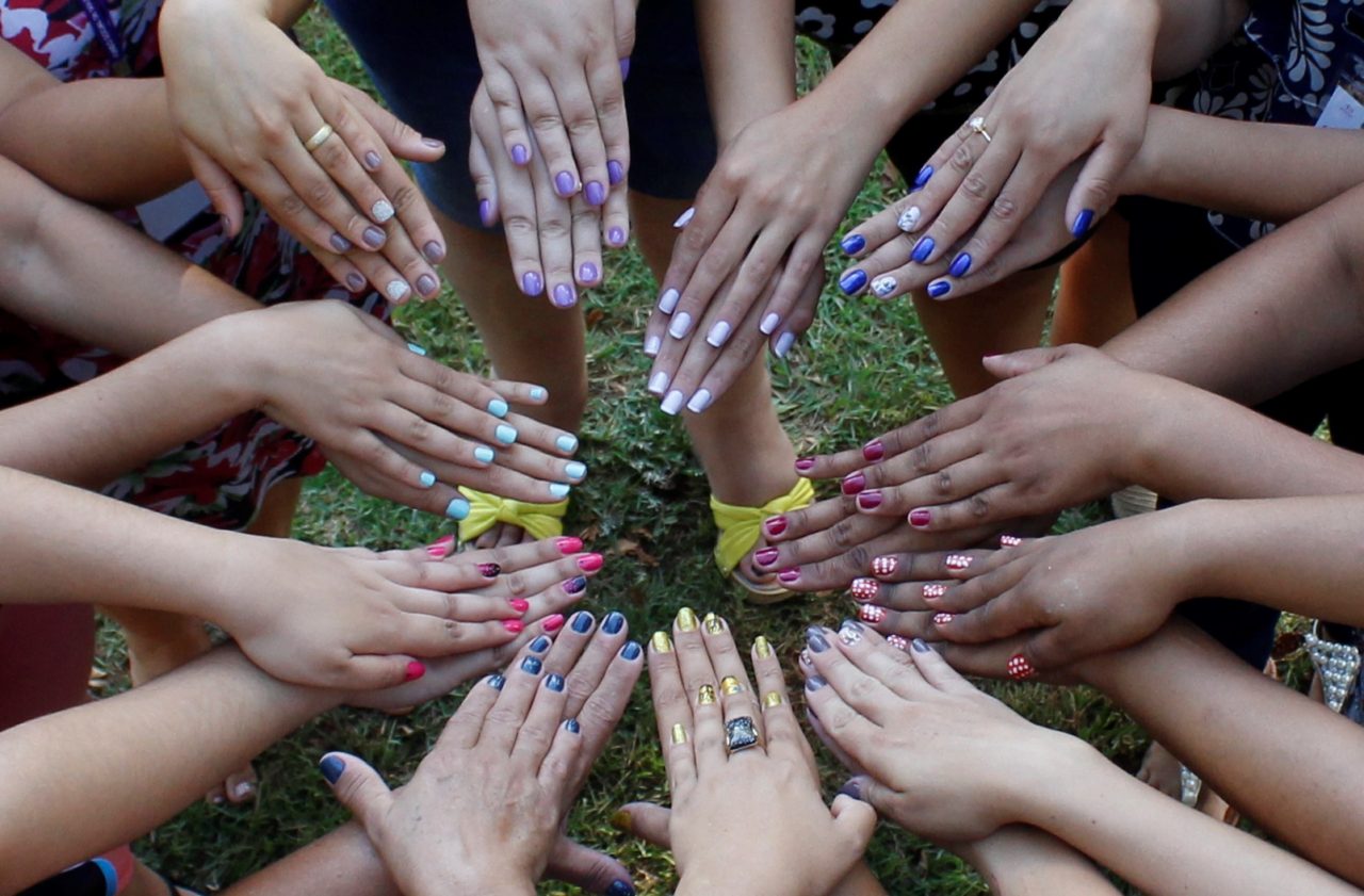 Mãos femininas com unhas esmaltadas em cores diversas
