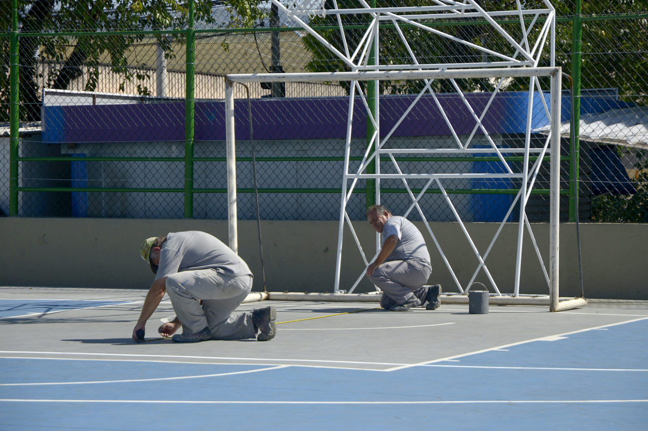 Pessoas jogando basquete em quadra poliesportiva pública na orla