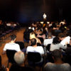 Auditório com pessoas sentadas e palestrante no palco