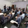 pessoas sentadas numa sala, acompanhando a fala do prefeito Luiz Fernando Machado