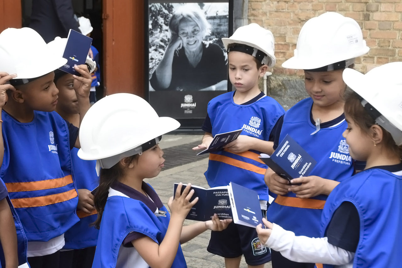 Crianças com coletes e capacetes personalizados , segurando passaportes e conversando