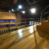 Chão de madeira de arquibancada de teatro, com palco e cortina aberta ao fundo