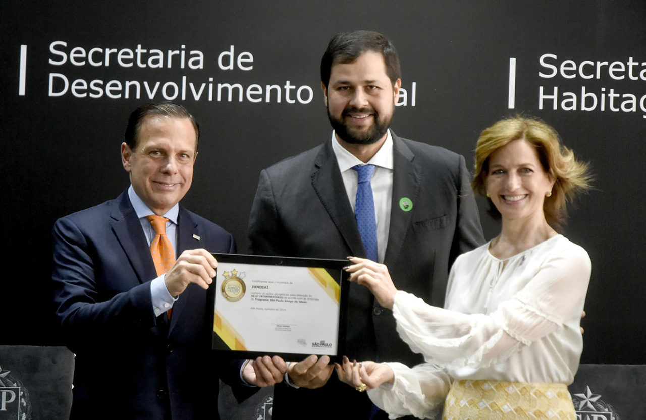 Foto posada do prefeito com o governador e secretária estadual, segurando certificado 