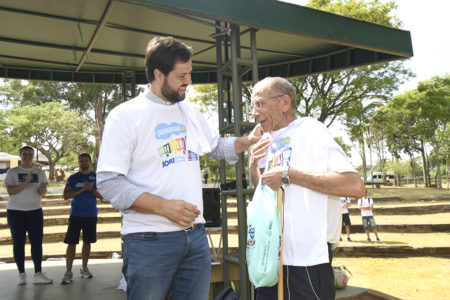 Homem conversando com idoso, entregando camiseta