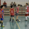 Quatro meninos com jaleco jogando futebol em quadra