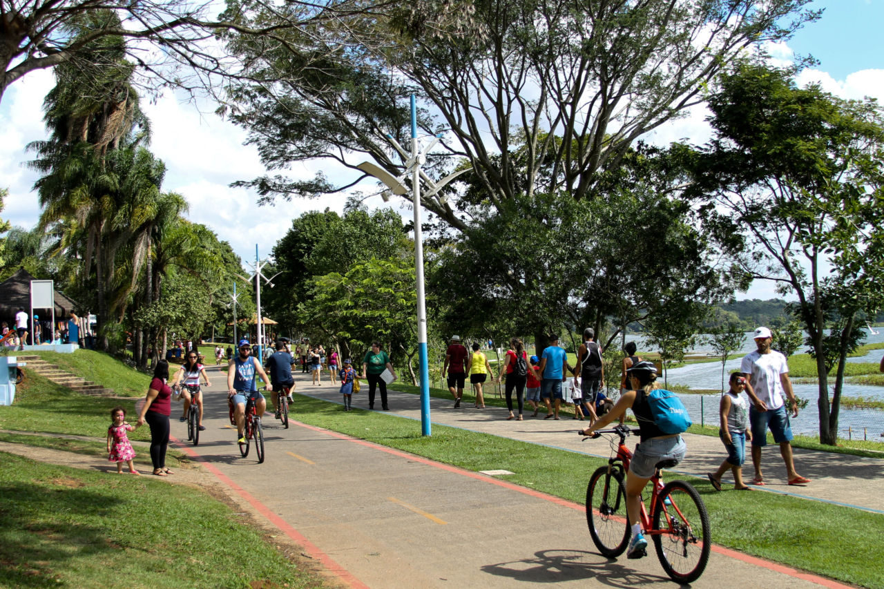 Parque com pessoas fazendo caminhada e andando de bicicleta