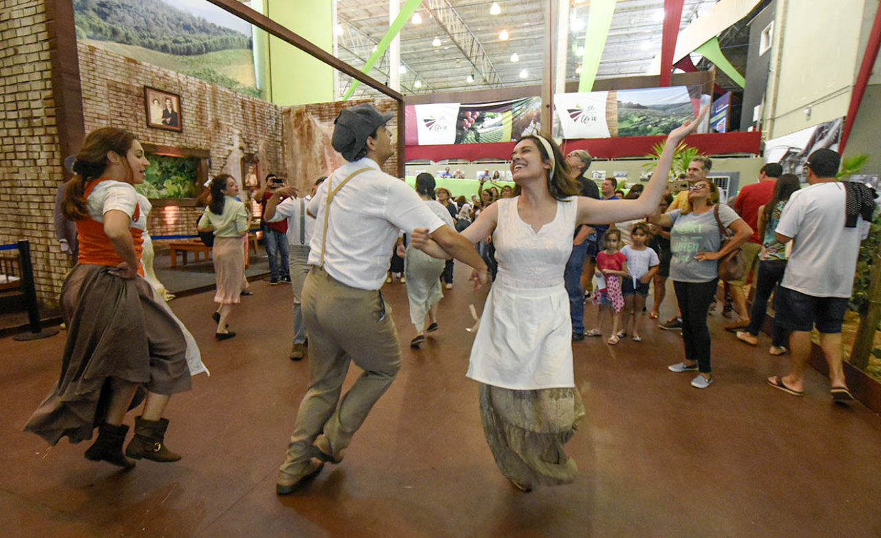 Pessoas com rioupas de imigrantes italianos, dançando em pavilhão