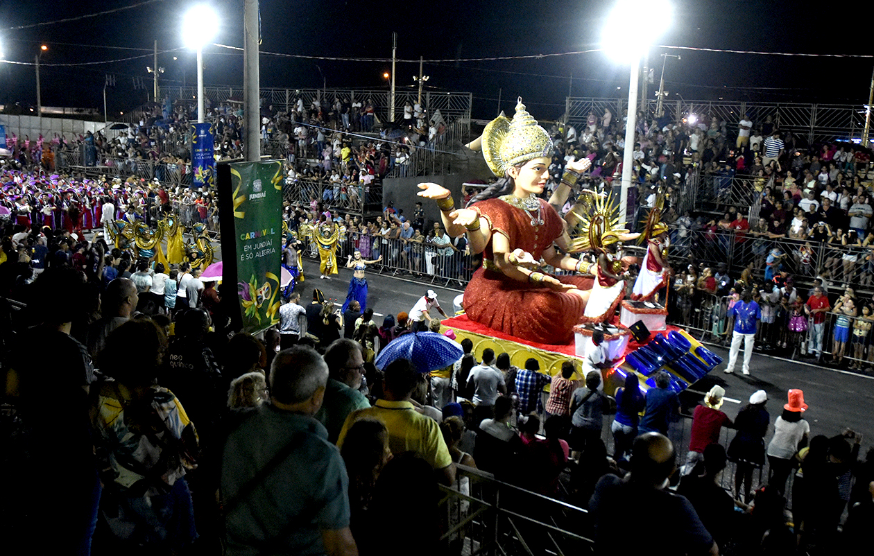 Local de desfile das escolas de samba, com público assistindo e carros alegóricos desfilando, com fantasias