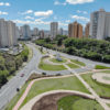 Foto aérea de avenida vazia, com edifícios no entorno e jardim com desenhos paisagísticos