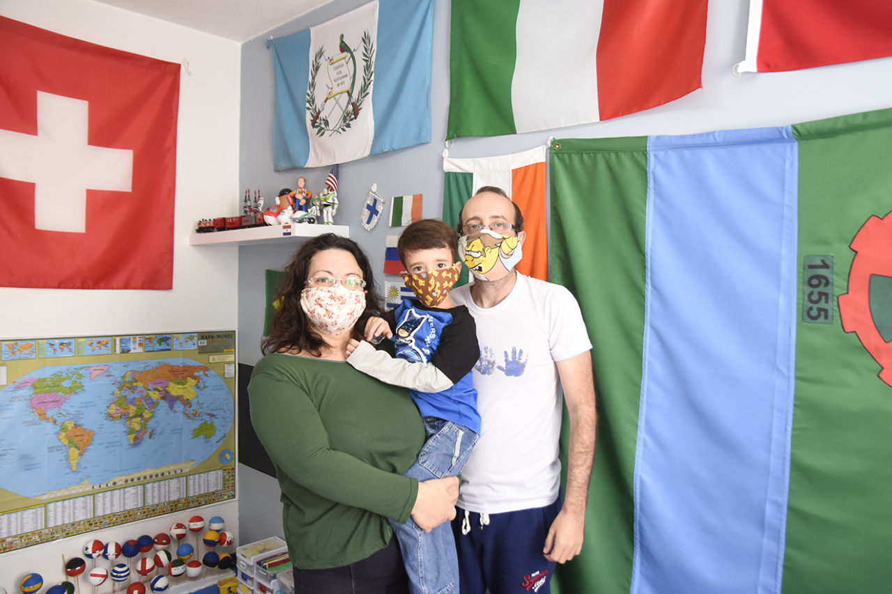 Ana Paula, Leonardo e Felipe, no quarto do garoto cheio de bandeiras na parede