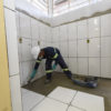 Operário coloca piso e azulejo no banheiro da EMEB Wilma Nalin Fávaro, no Santa Gertrudes