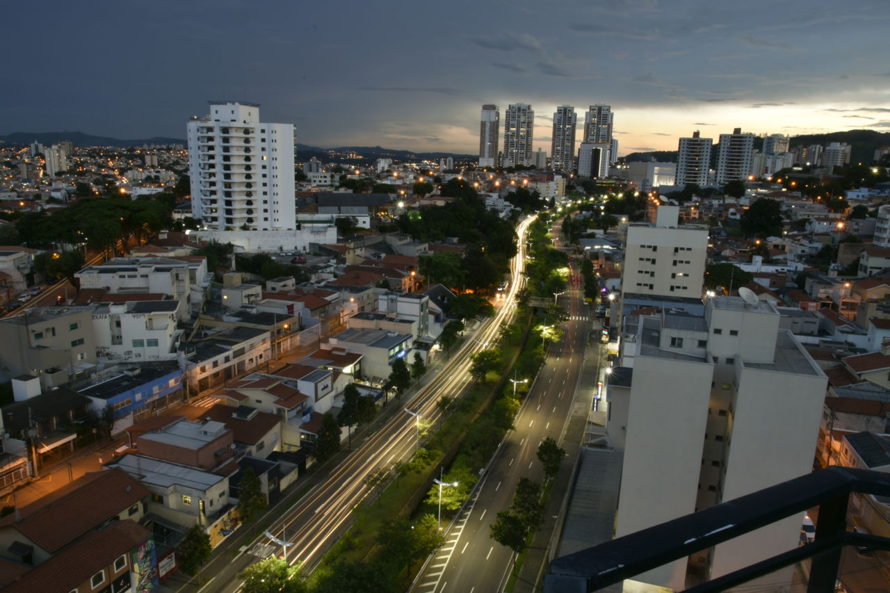 Imagem noturna de Jundiaí, com prédios e avenida iluminada