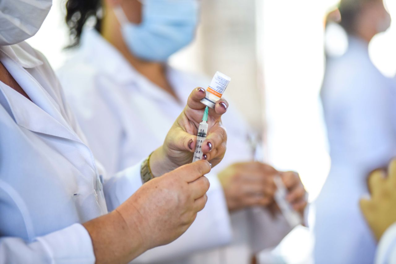 Imagem mostra enfermeiras fazendo a aspiração - retirada das vacinas - para a seringa.