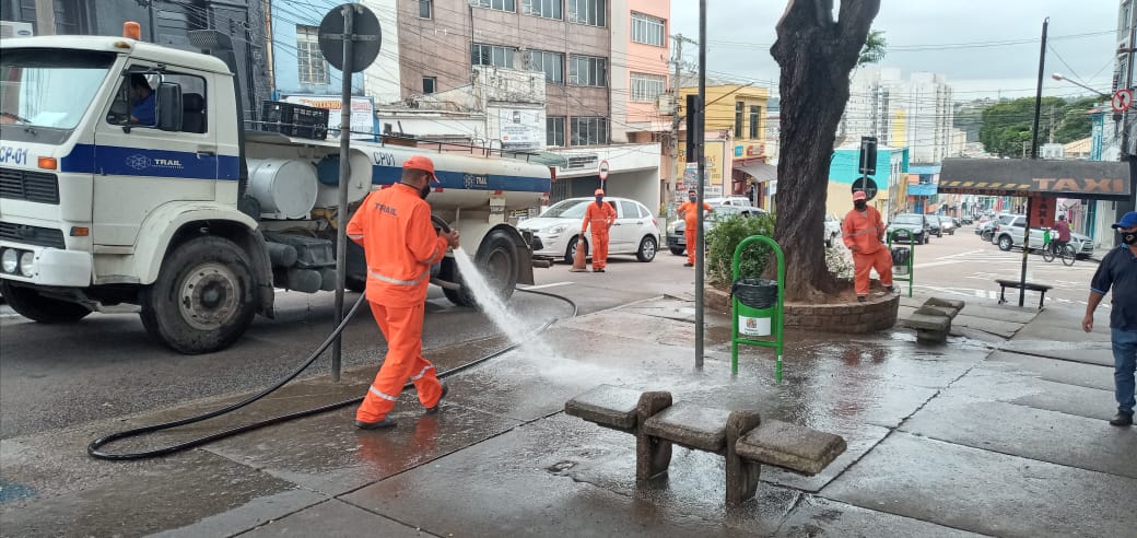 Homens da equipe de limpeza da prefeitura lavam uma praça
