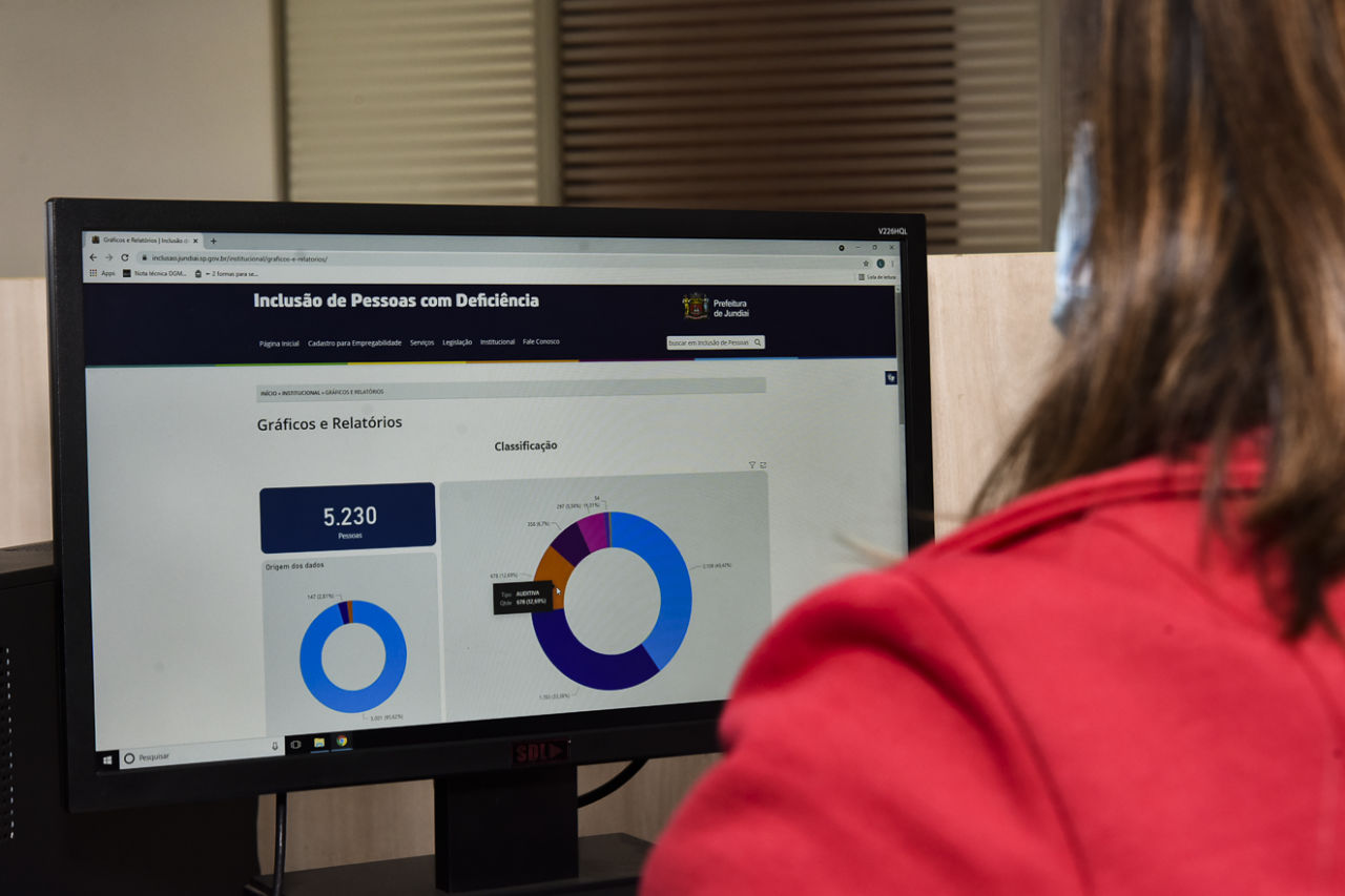 Imagem mostra mulher em frente à tela de computador. Na tela, site Inclusão de Pessoas com Deficiência