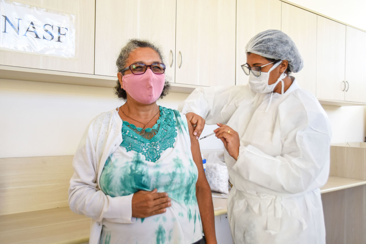 Imagem mostra enfermeira aplicando vacina em idosa. 