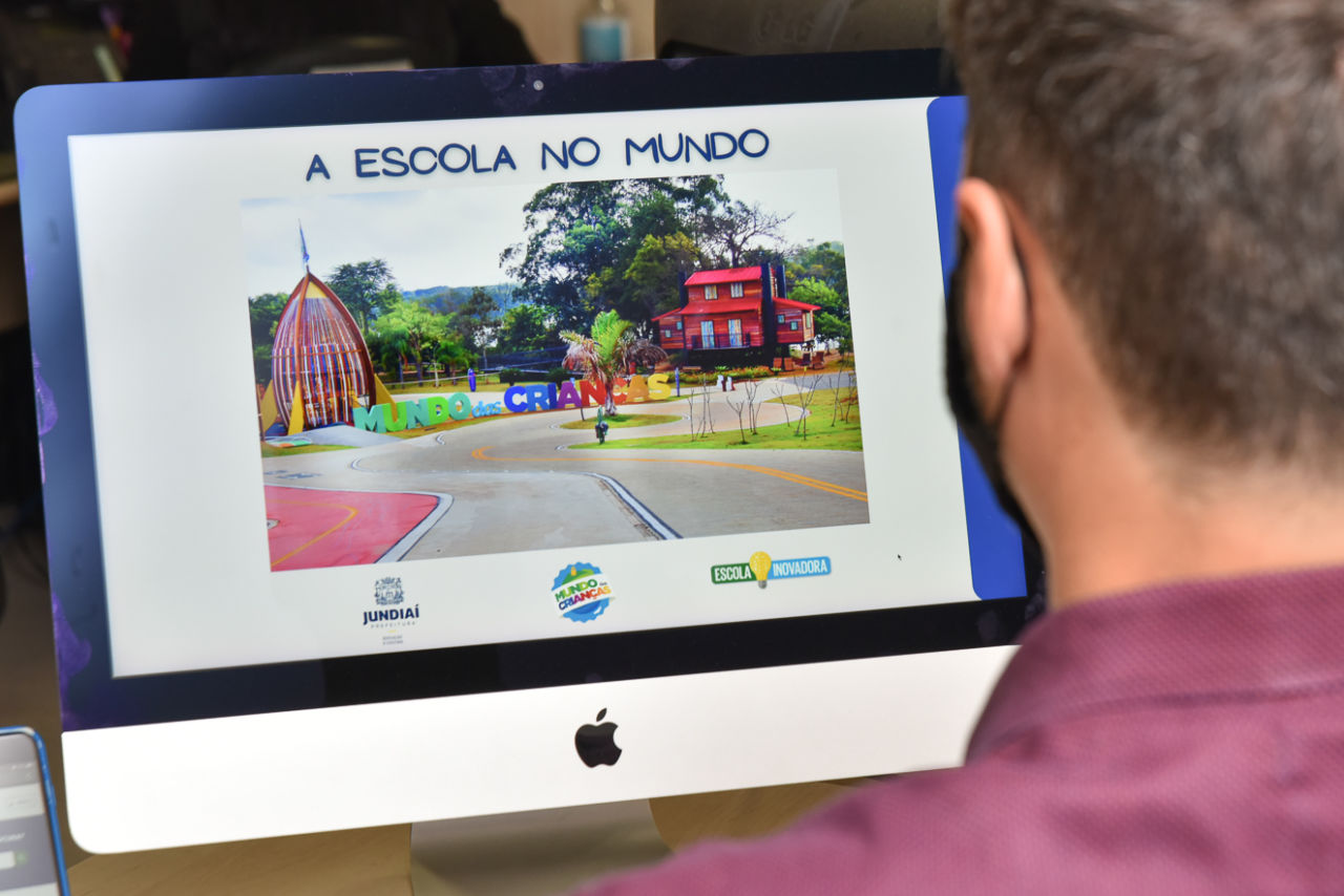 Imagem mostra homem olhando para tela de computador. Na tela capa do e-book A escola no Mundo