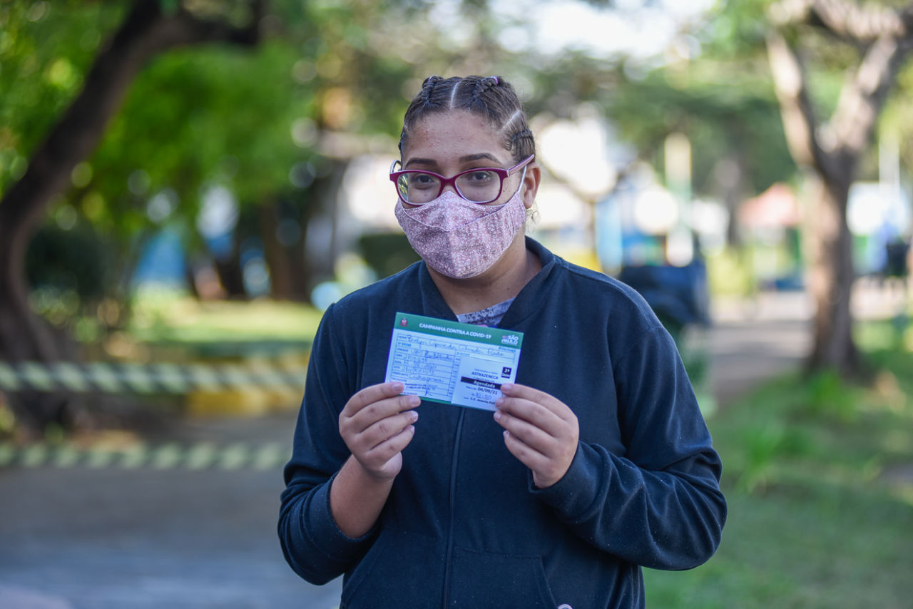 Imagem mostra mulher segurando cartão de vacinação na mão