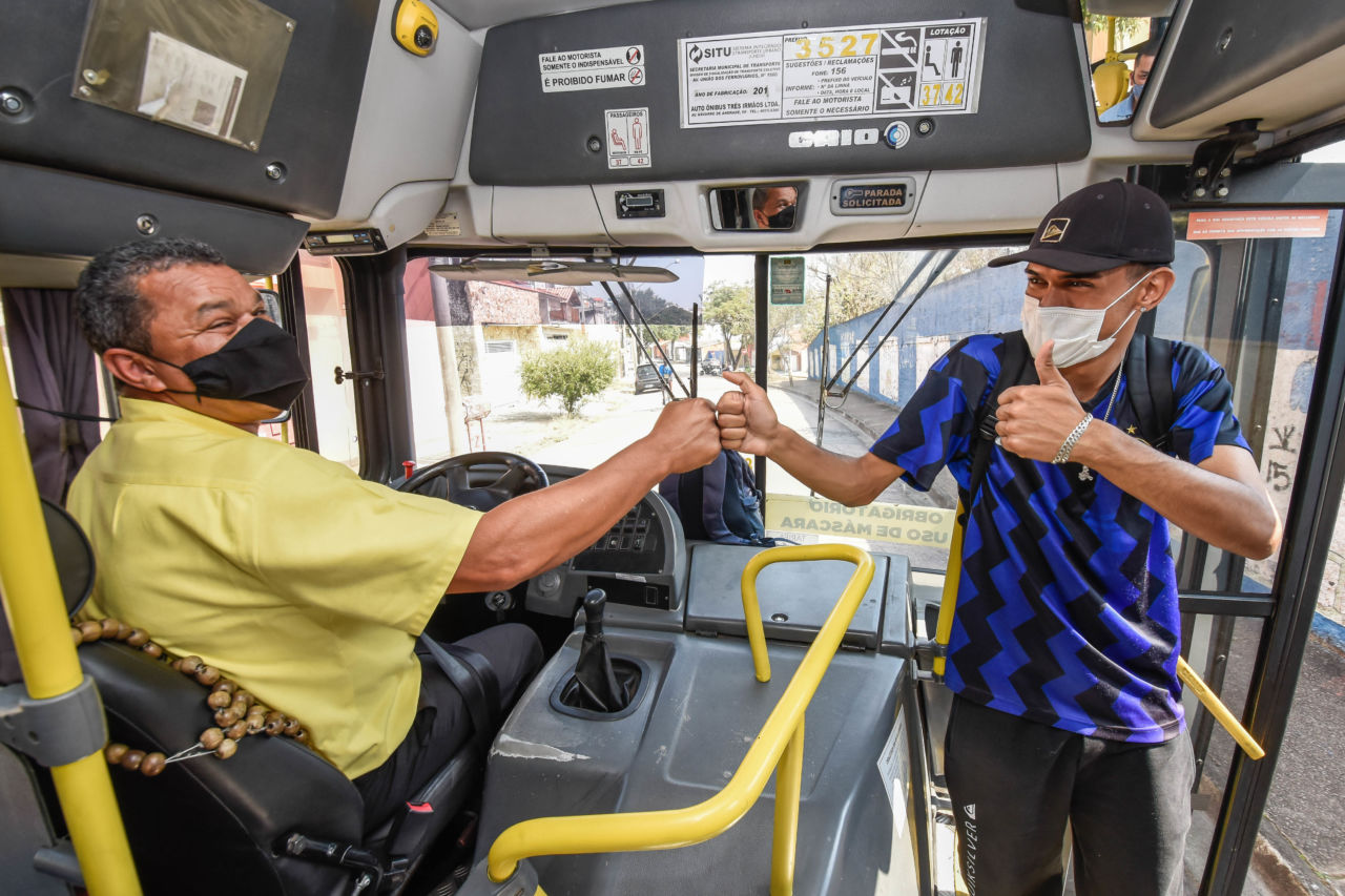 O motorista Divino cumprimenta o estudante Thiago no interior do ônibus