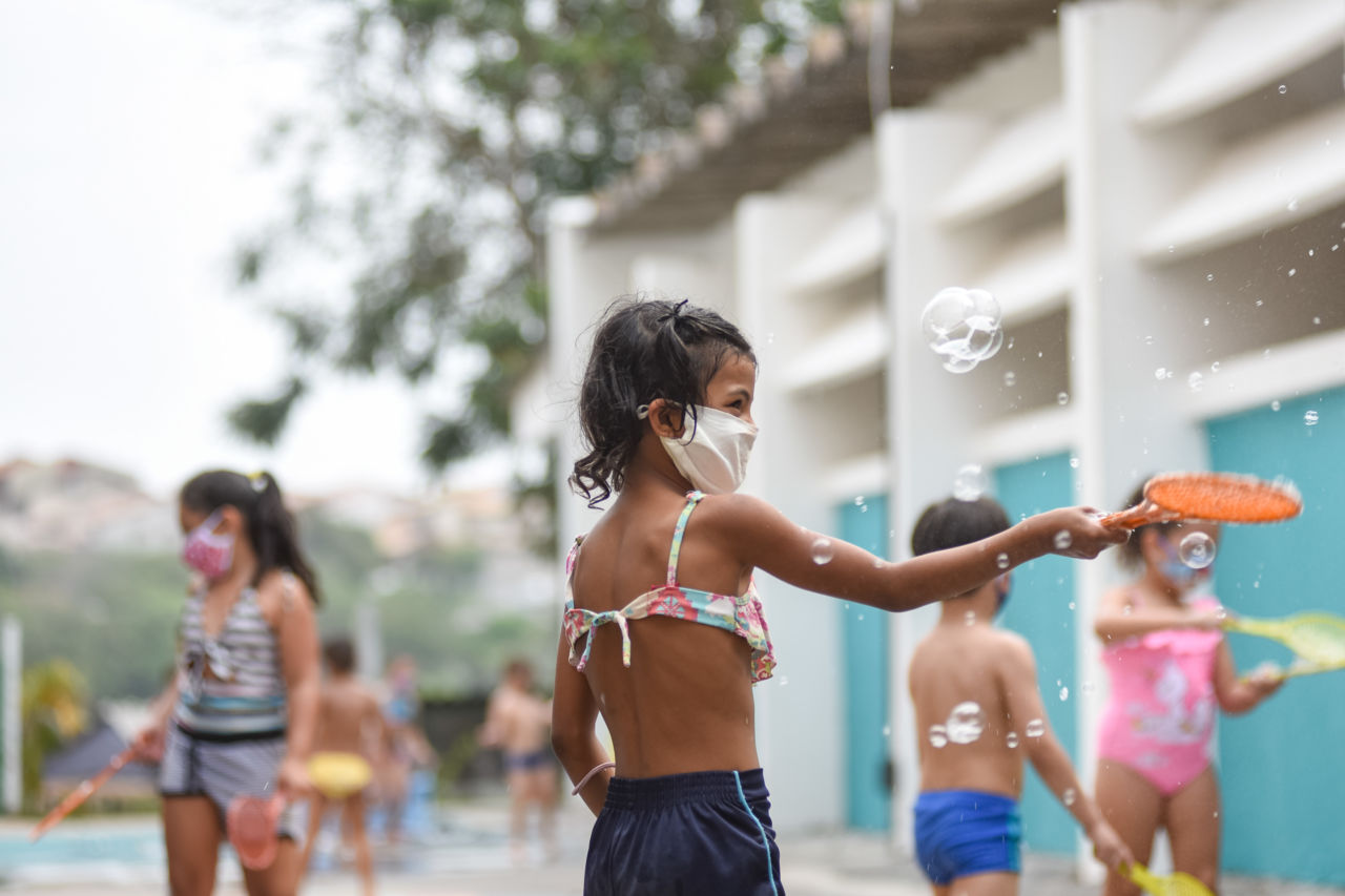 crianças estão com roupa de banho e brincando com bolinhas de sabão