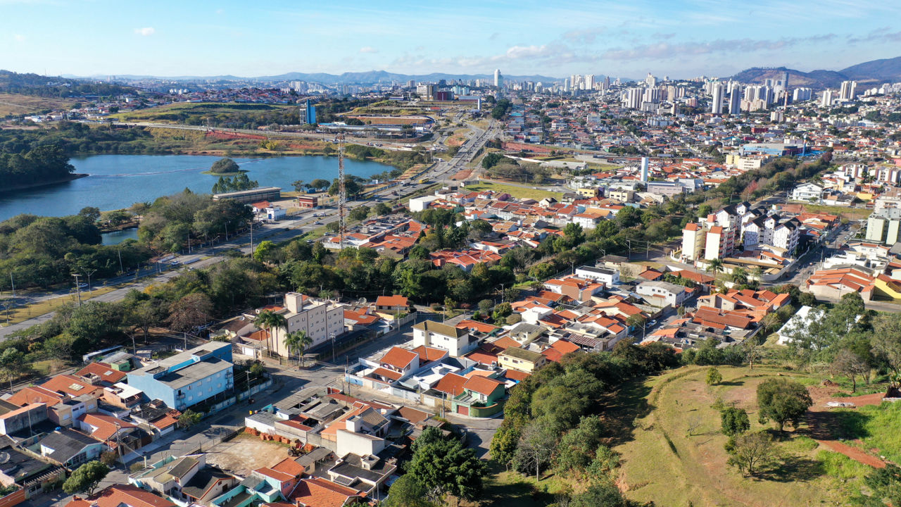 DESCRIÇÃO DA IMAGEM
Imagem aérea da cidade, na qual pode-se avistar prédios, casas, represa ao lado esquerdo da foto, corredores de árvores e de área verde