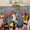 Palhaços fazem show em palco com cortinas coloridas