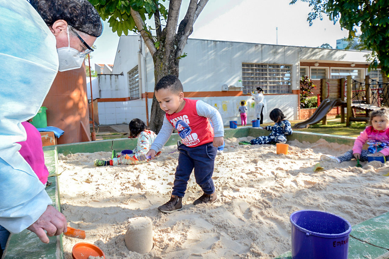 Crianças brincam em um tanque de areia.