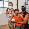 Pai e dois filhos mostram o braço após receberem a dose da vacina contra a covid 19