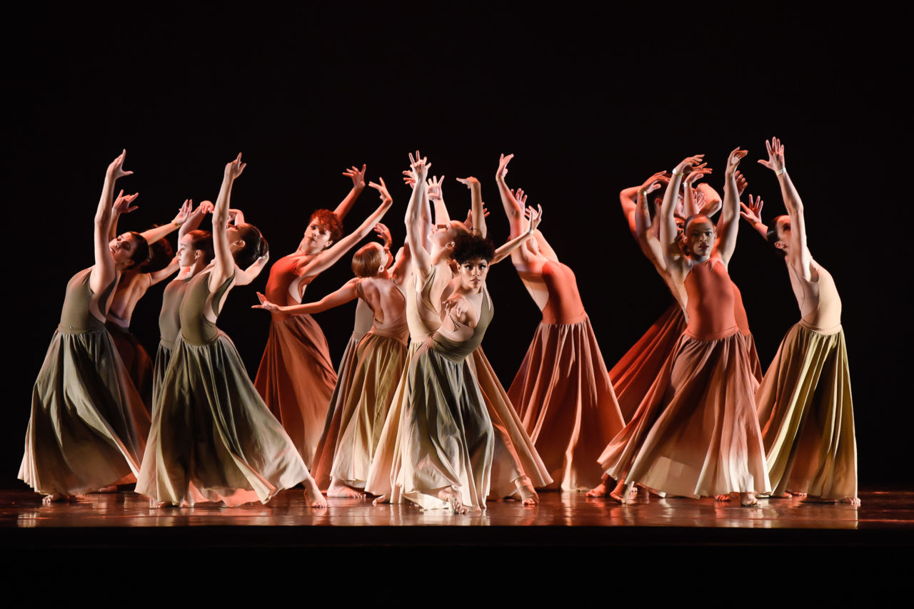 Bailarinas com vestidos longos em performance em palco iluminado