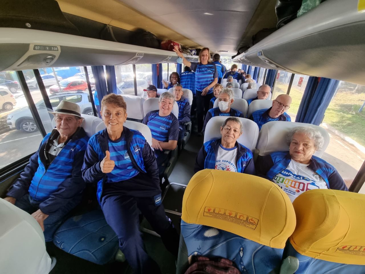 Idosos do TIME Jundiaí, com agasalho azul, dentro do ônibus que os levará para os Jogos da Melhor Idade