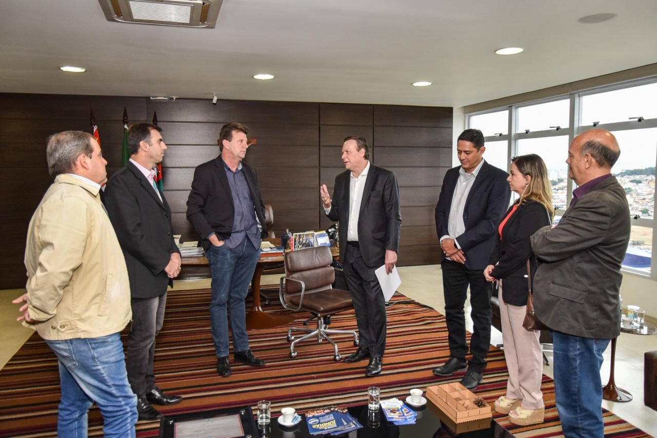 Gestores e prefeito de Sorriso-MT conversam de pé no gabinete do prefeito Jundiaiense durante reunião