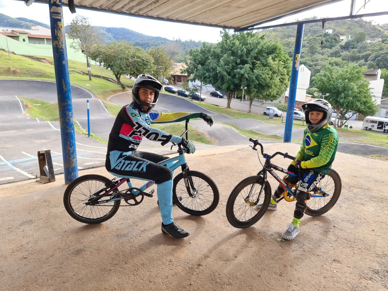 Luca e Andrey, montados em suas respectivas bicicletas, vestindo roupas e capacetes adequados, na pista de Bicicross de Jundiaí