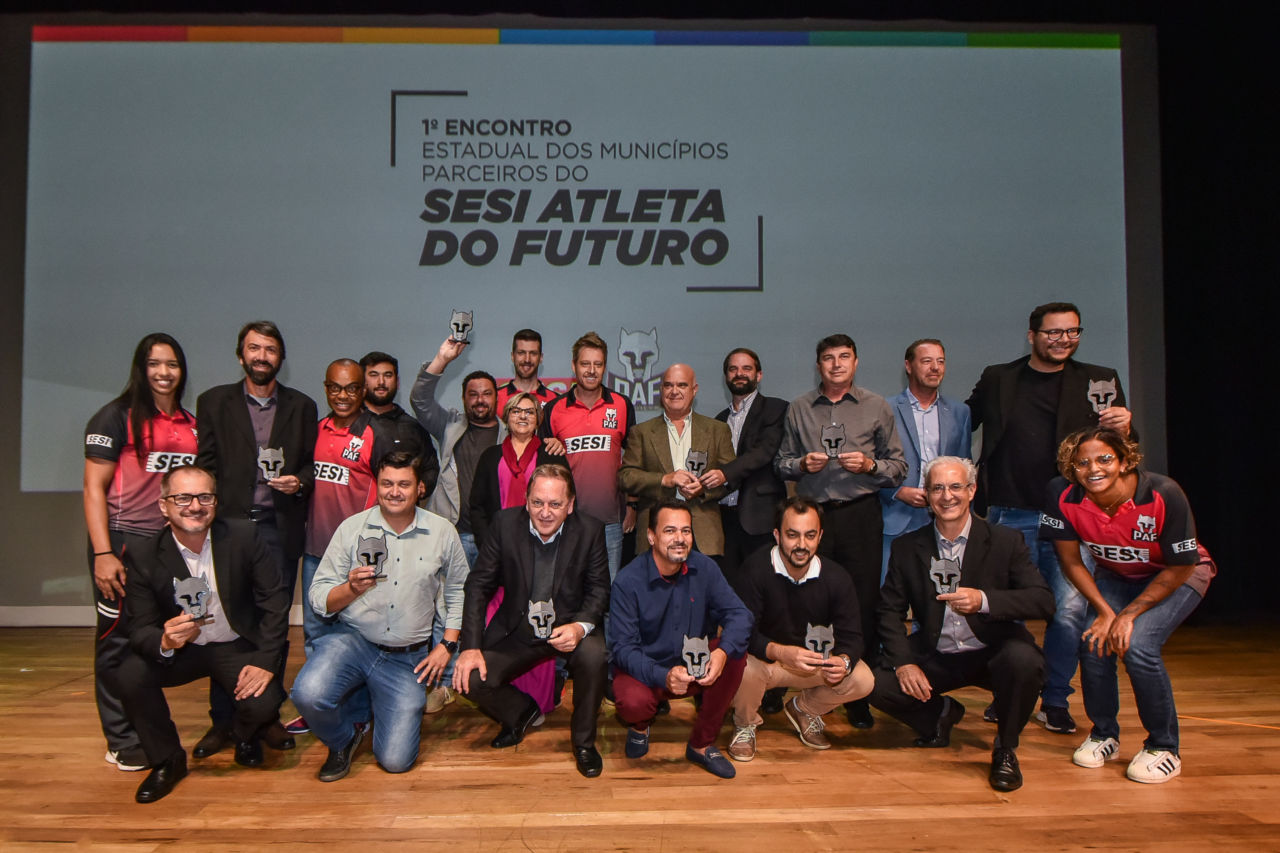 Prefeitos e secretários de esporte mostram o troféu dos municípios parceiros do SESI no palco do Teatro do SESI-SP