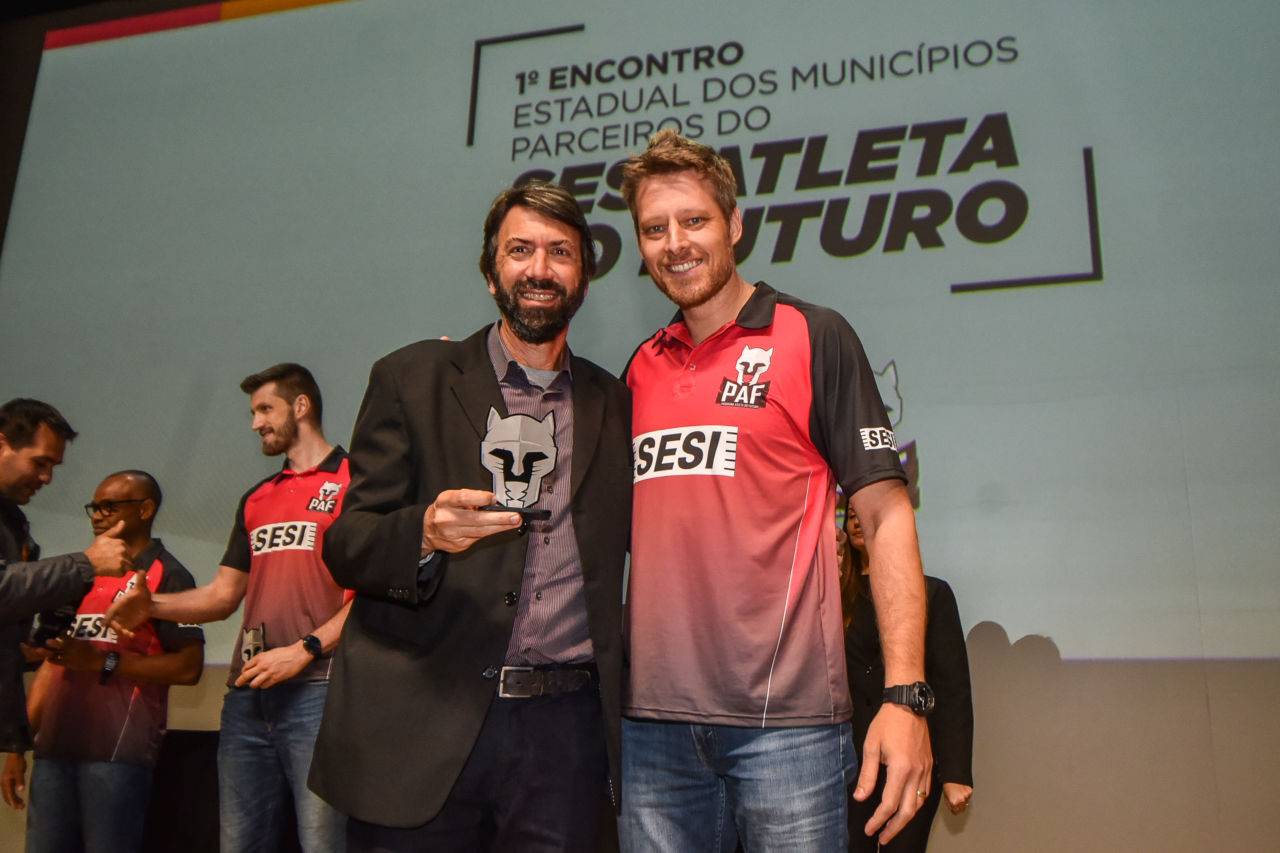 Gestor Tarallo posa, segurando o troféu, com o atleta Murilo, do voleibol do SESI e ex-atleta da Seleção Brasileira