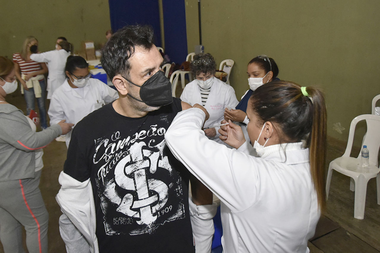 homem de máscara é vacinado por enfermeira